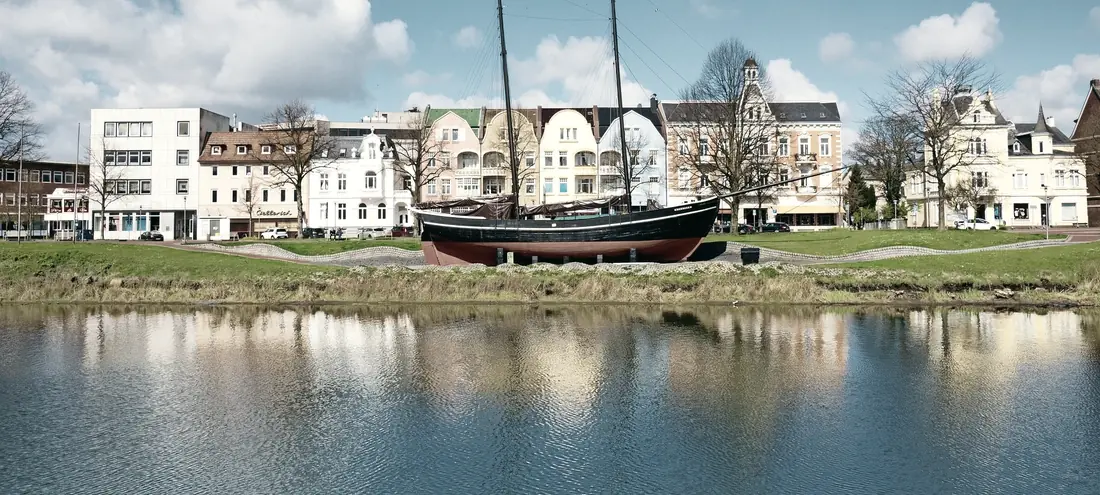 Historisches Segelschiff am Wasser vor einer Häuserzeile in Cuxhaven
